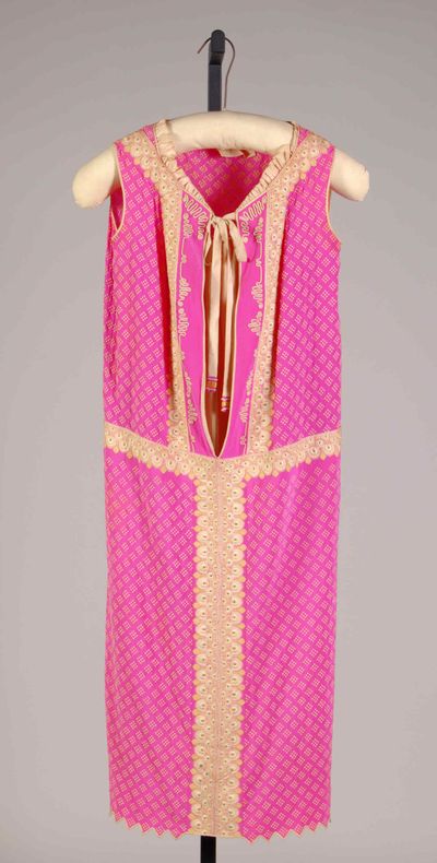 A sleeveless pink silk dress of about 1925 by the House of Lucile, hanging straight from the shoulders with no waist shaping, trimmed with cream embroidered bands.