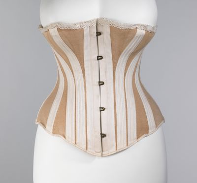 A cream and tan cotton corset of about 1885 by the Worcester Corset Company, shown on a dress form, with its shaped panels, boning channels and front busk visible.