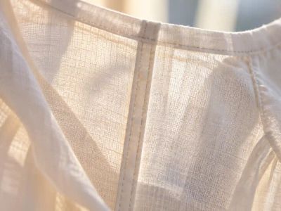 Close-up of a narrow French seam inside a sheer cream blouse, with light shining through the fabric around the enclosed seam.