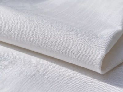 Close-up of folded white cotton poplin, showing its smooth, tightly woven surface.